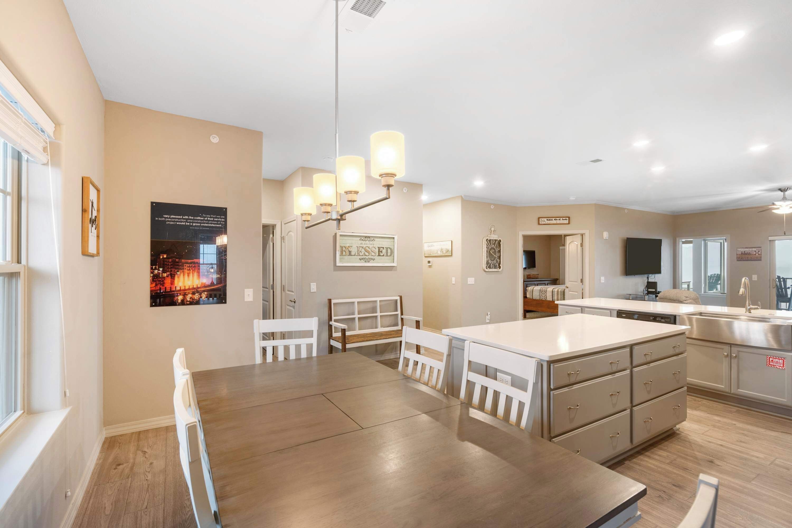 A modern kitchen with a central island, white cabinetry, and a dining area with a wooden table and chairs.