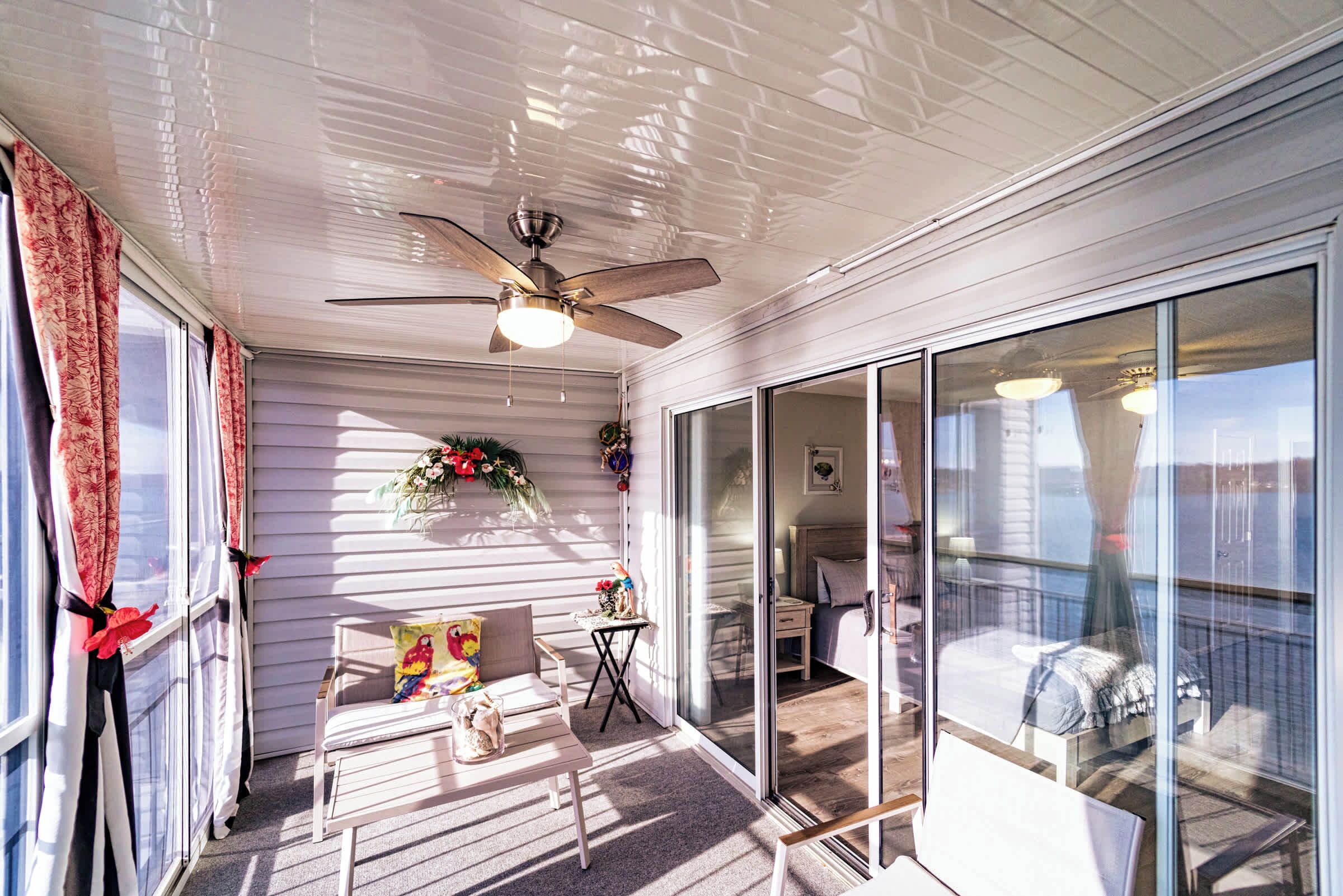 A covered patio with a ceiling fan, a small table with chairs, and a view into the adjacent room.