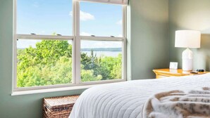 A bedroom with a large window offering a view of a lake and trees. - Sunset Daydream Elegant Condo on Table Rock! (Branson)