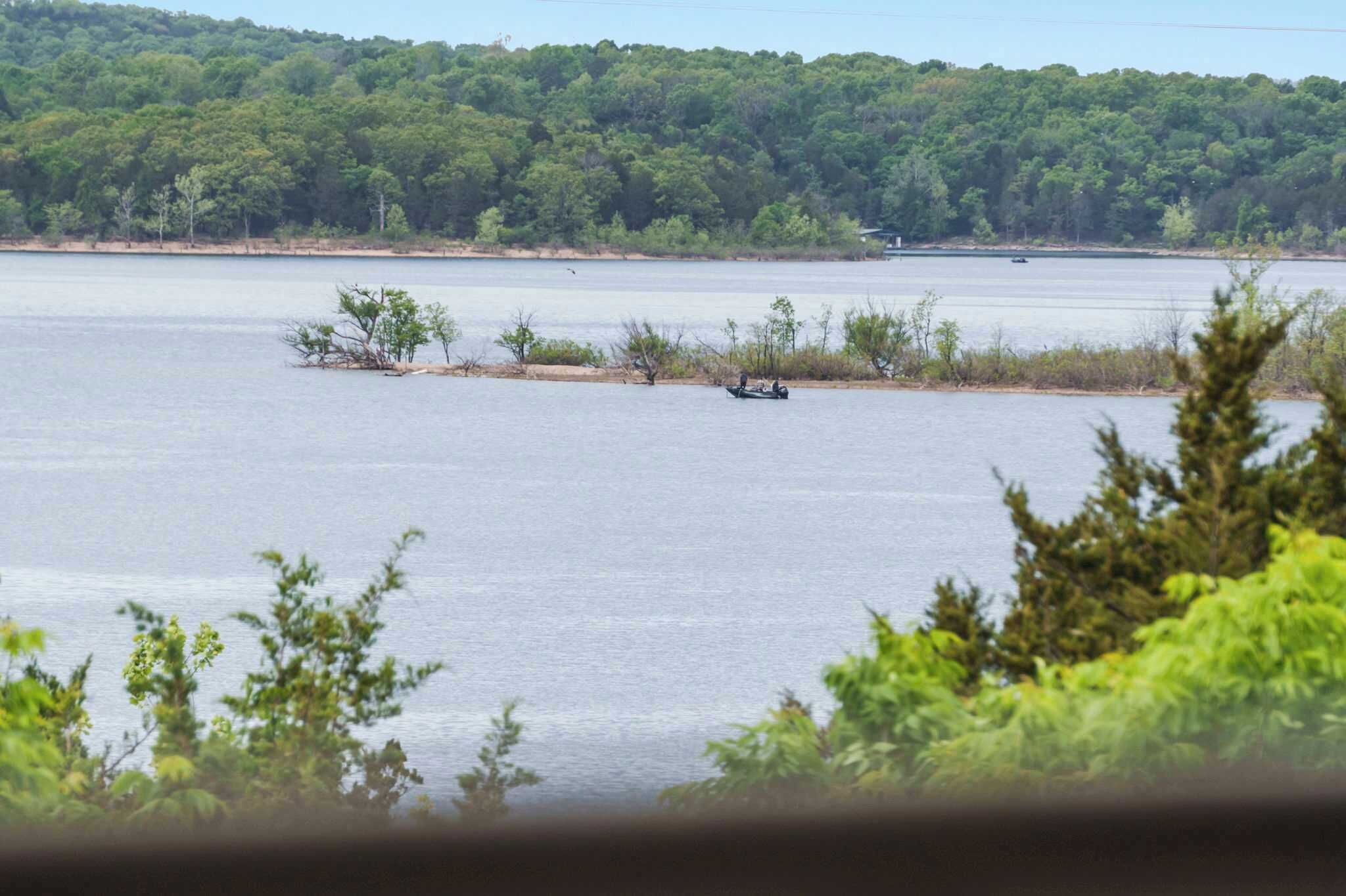 A lake with a boat in the distance, surrounded by dense forest.