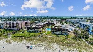 A coastal hotel with multiple buildings, a swimming pool, and a beach area.