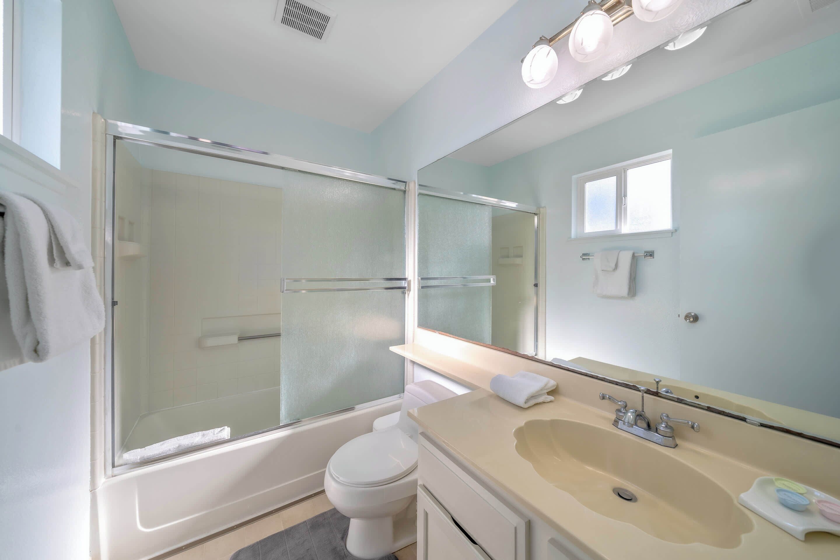Une salle de bain moderne avec une douche à parois de verre, une baignoire, des toilettes et un lavabo avec un miroir au-dessus.
