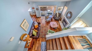 A spacious living area with a wooden staircase, a leather sofa, and a dining table. - Succulents & Seashells Coastal Paradise by Beach (Marina)