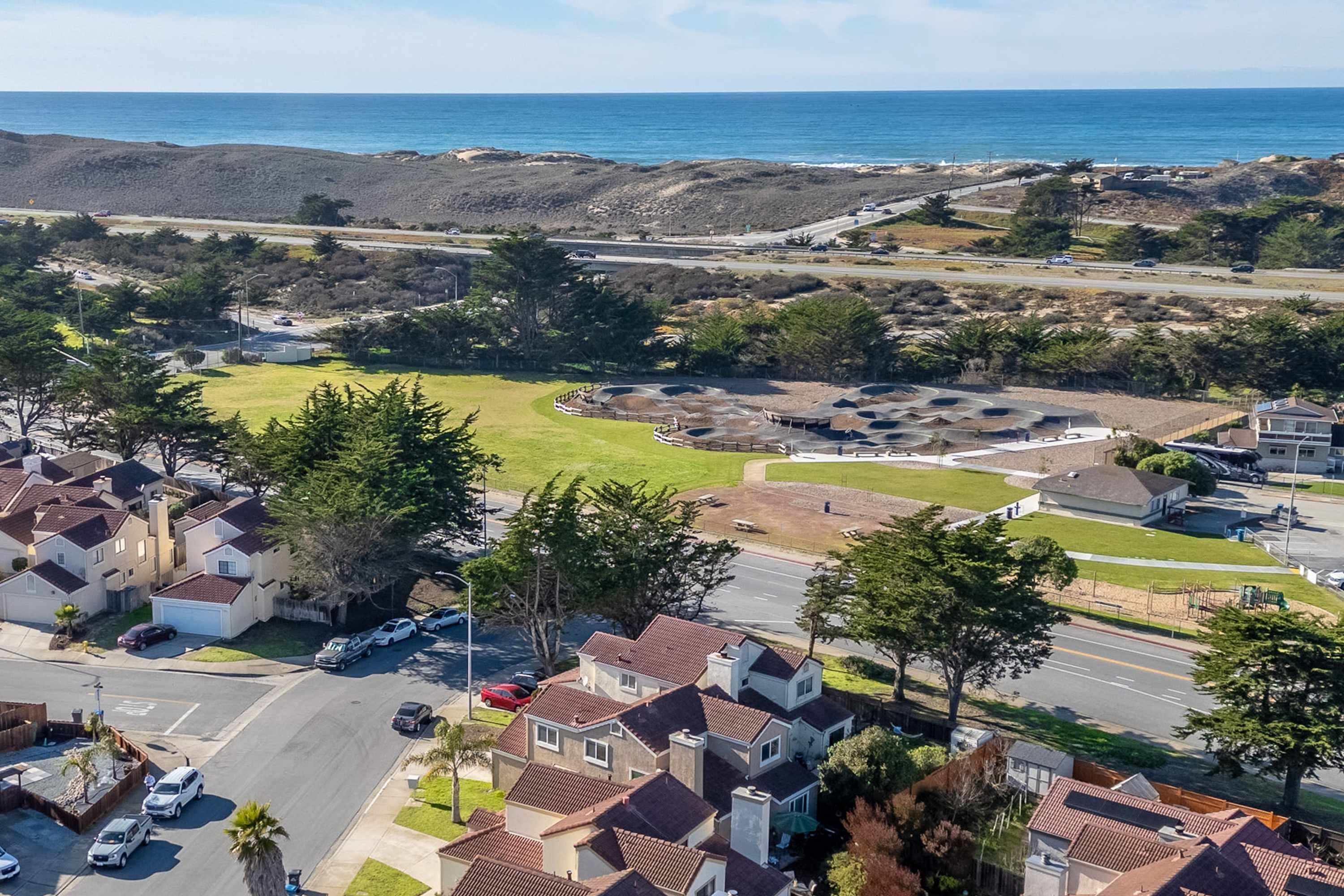 Un quartier résidentiel avec des maisons, une route et une plage en arrière-plan.