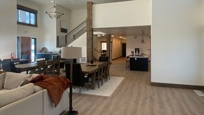 Ein geräumiger Wohnbereich mit Esstisch, Sofas und einer Treppe, die in einen oberen Bereich führt.