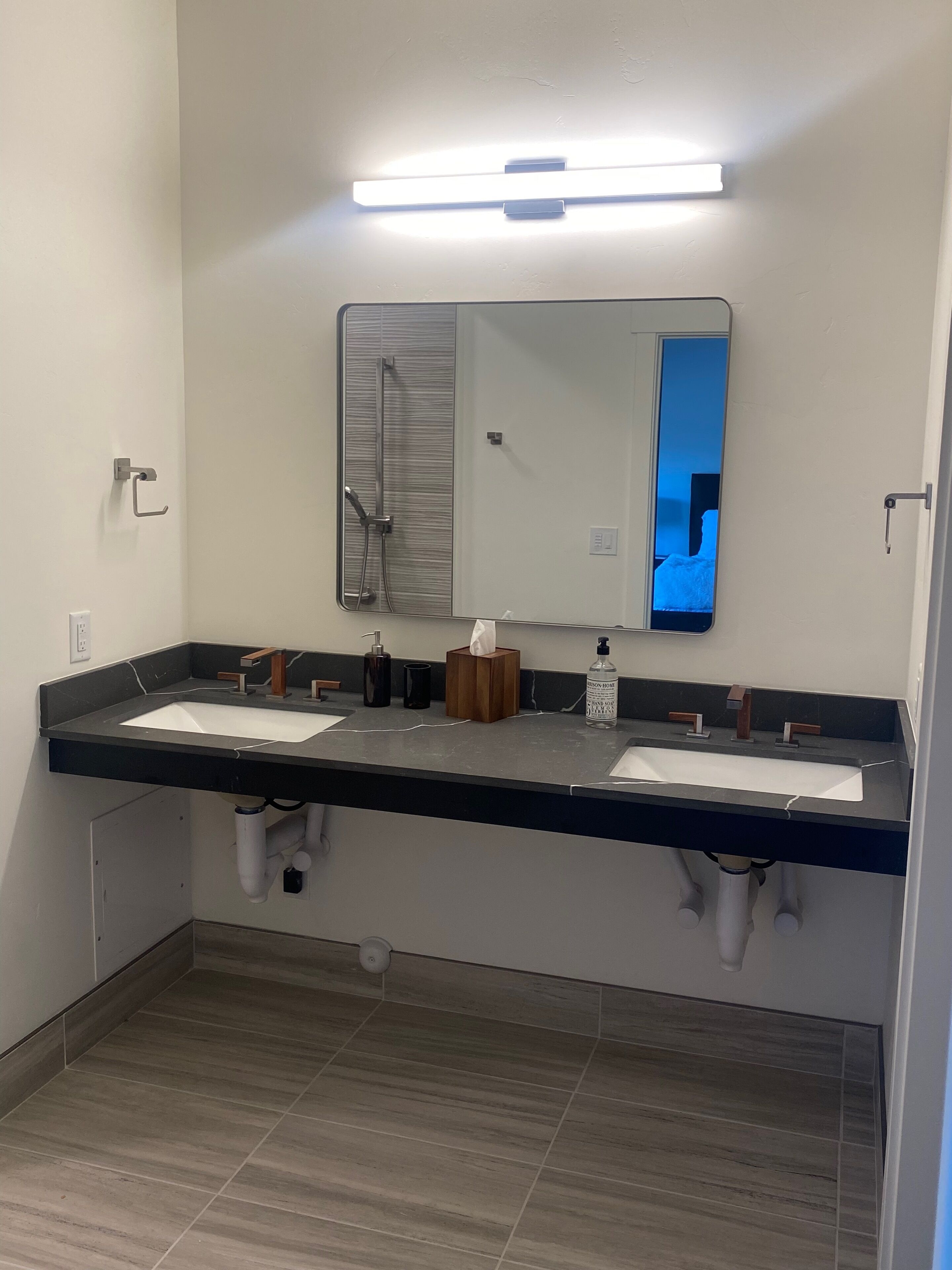 Un baño moderno con dos lavamanos, un espejo grande y una ducha.
