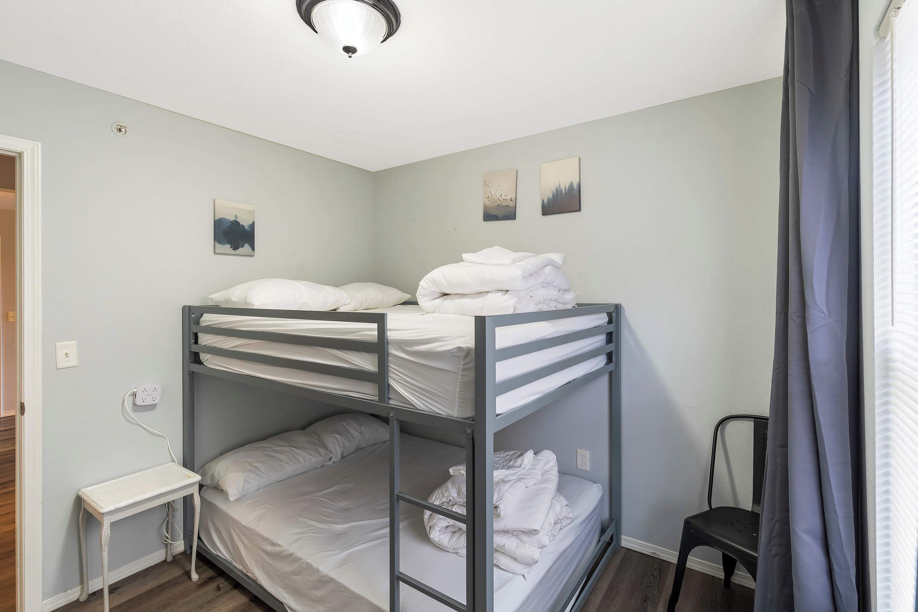 A bunk bed room with a small table and a chair.