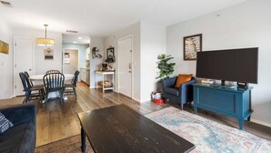 Een woonkamer met een televisie, bank en een eethoek.