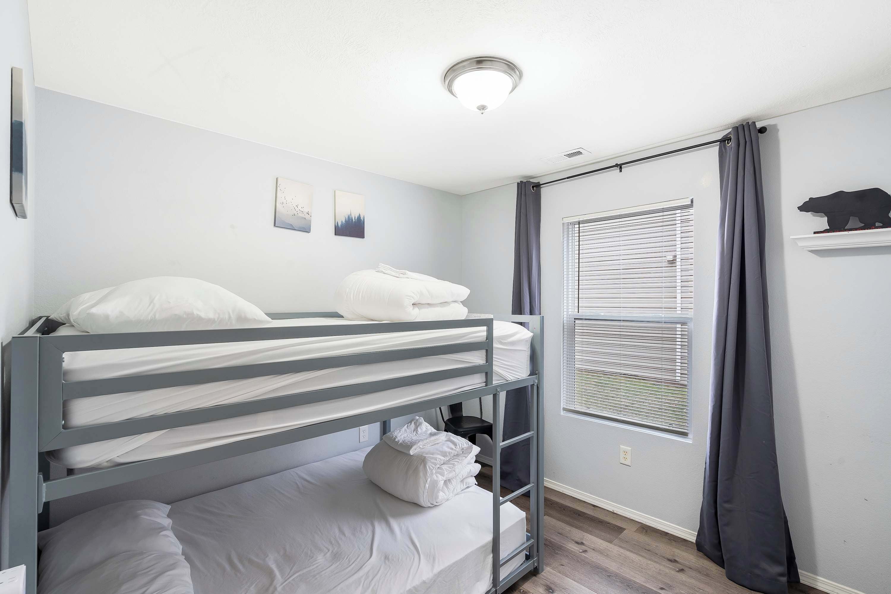 A bunk bed room with a window and a bear decoration on the wall.
