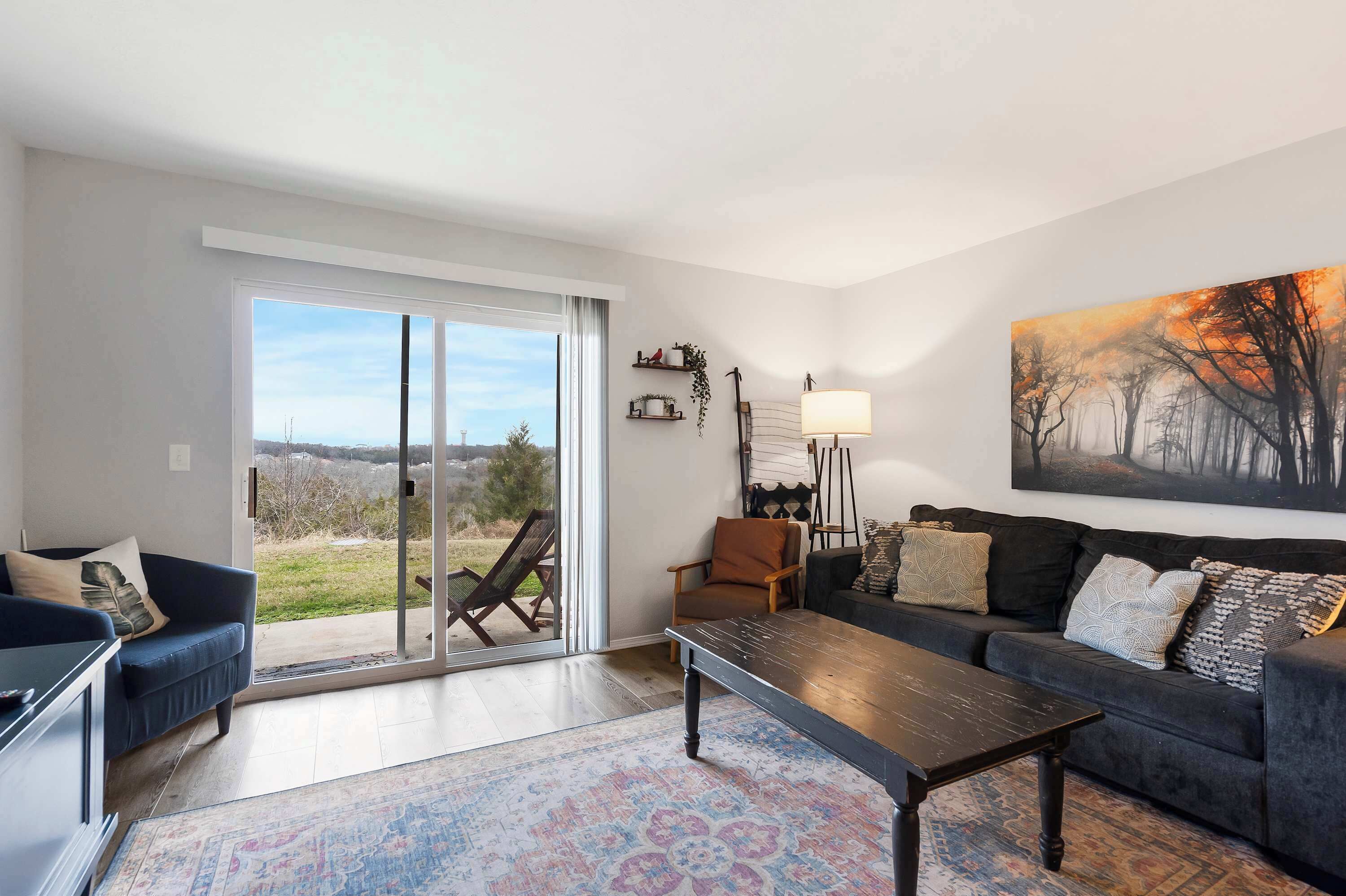 Un salon comprenant un canapé, un fauteuil et une table basse. Une grande fenêtre offre une vue sur l’extérieur.