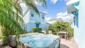 A hot tub in a backyard with a patio, a table, and chairs. - Frankly Fintastic (Kissimmee)
