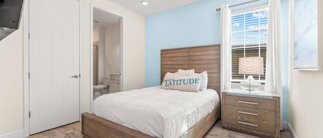 A bedroom with a wooden bed, a nightstand, a ceiling fan, and a window with curtains.