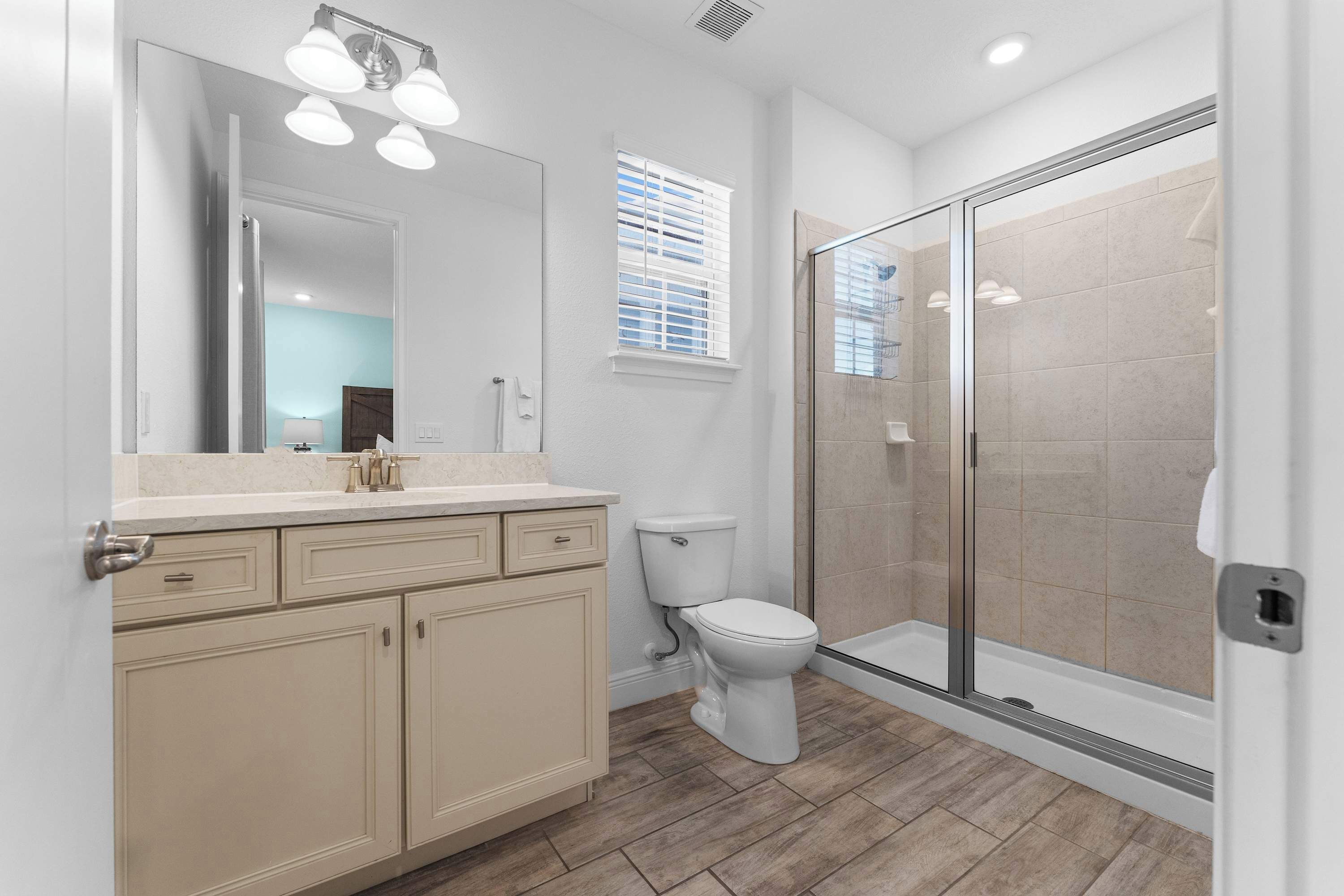 Un bagno moderno con doccia vetrata, un mobile lavabo beige con specchio e un water.