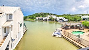 A riverside hotel with a swimming pool, docked boats, and a view of a hill with buildings. - Lakeside Hideaway (Horseshoe Bay)