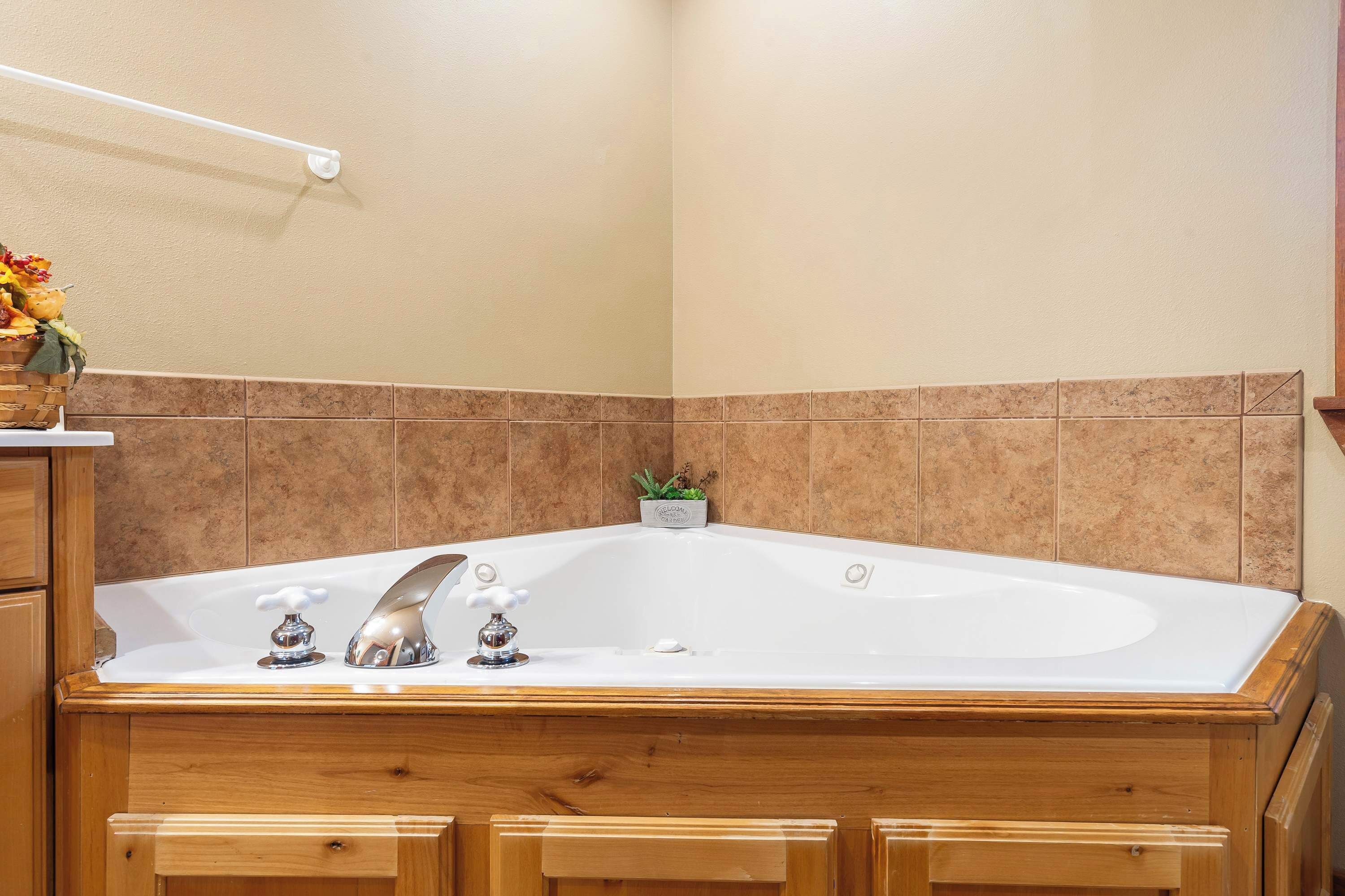 A bathroom with a freestanding bathtub, wooden cabinetry, and a tiled backsplash.