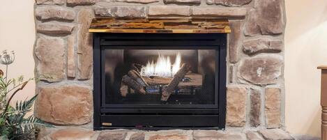 A stone fireplace with a fire burning inside.