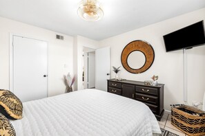 Cozy retreat with a large bed, dresser, and flat-screen TV.