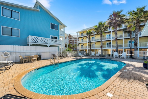 Relax by the pool surrounded by palm trees and lounge chairs.