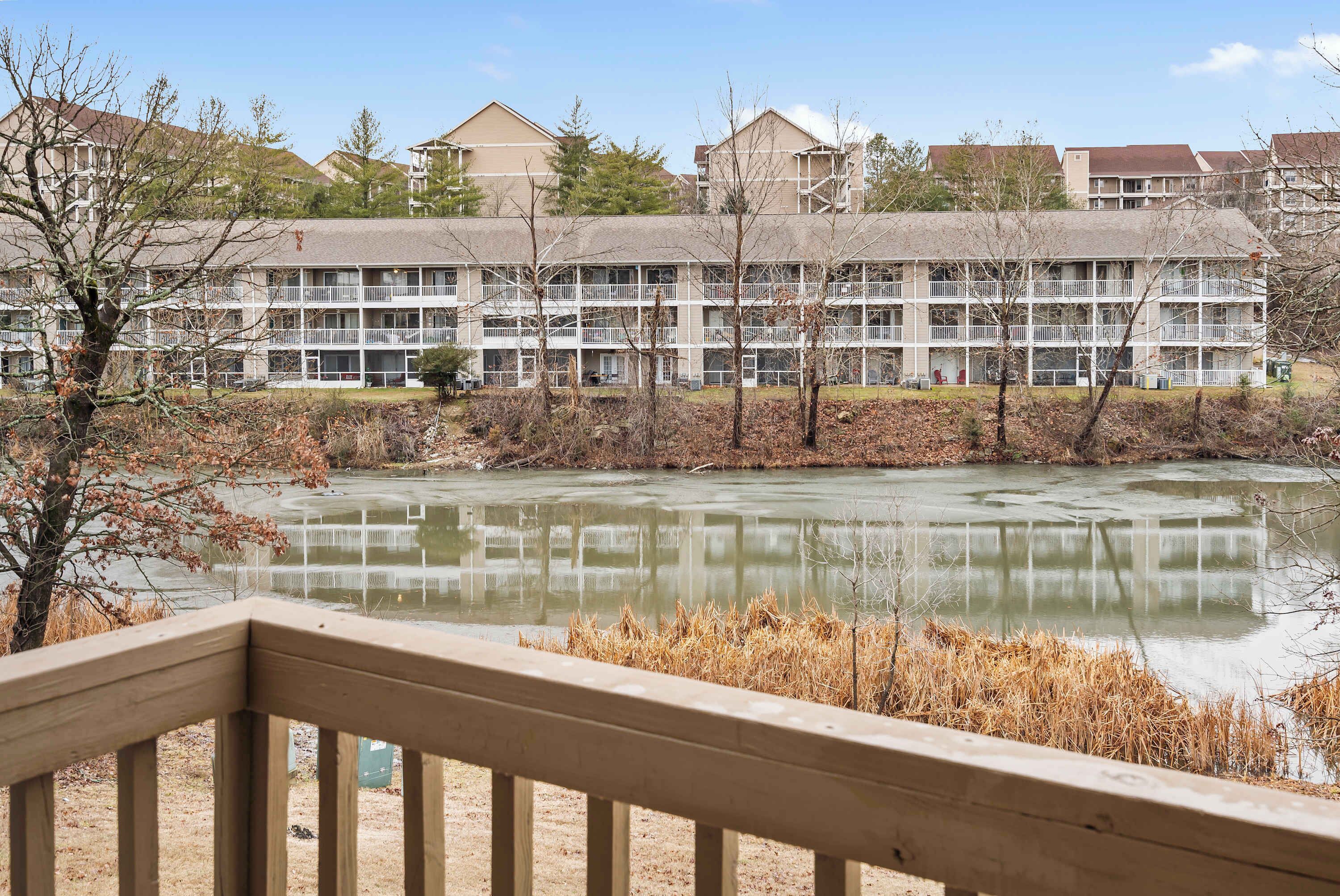 A multi-story hotel with balconies, a pond in the foreground, and a clear sky.