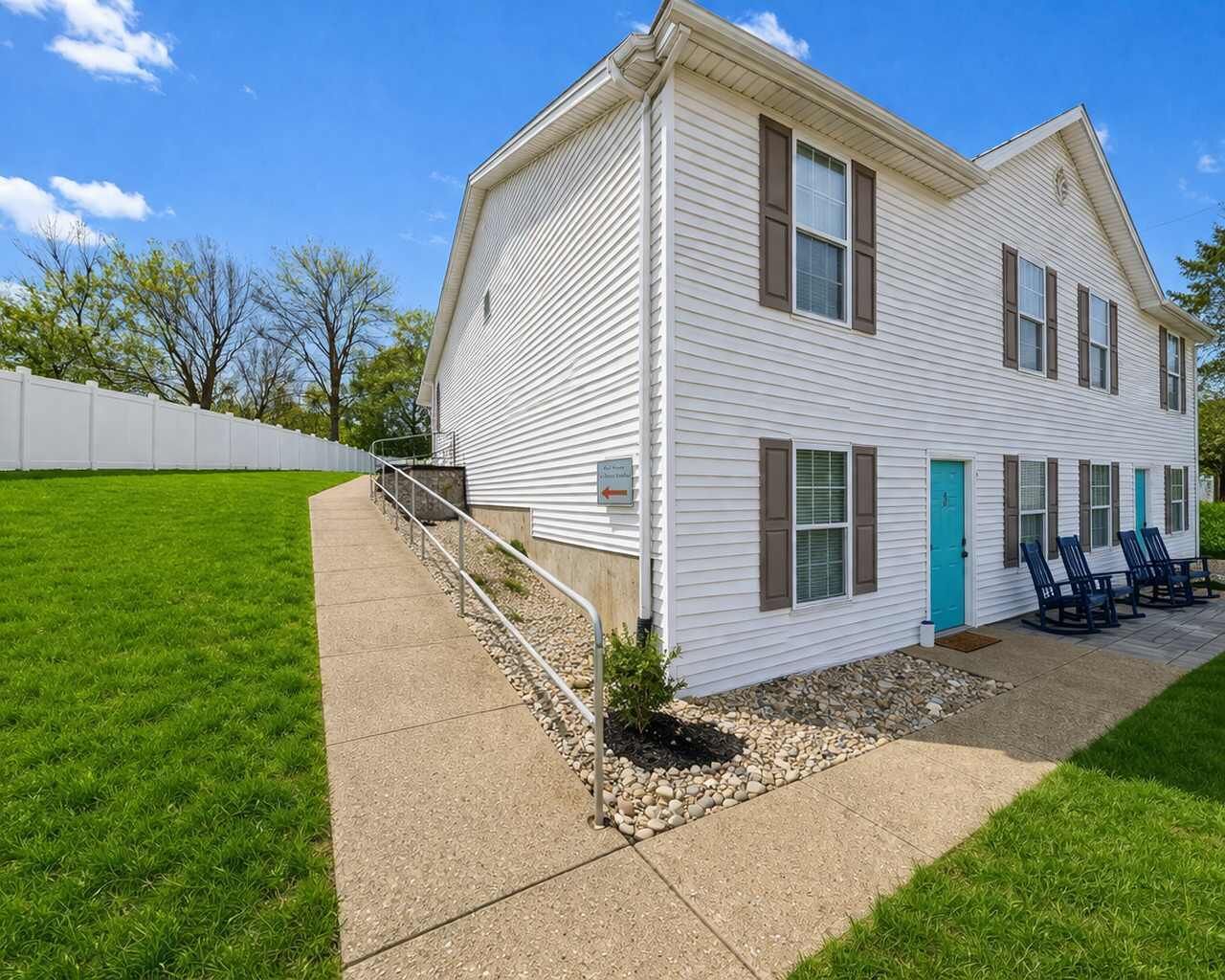 A two-story building with a front porch, a small garden area, and outdoor seating.