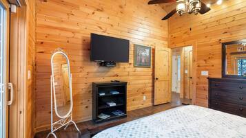 Una habitación con paneles de madera, una cama, un televisor, un espejo y una puerta señalizada con