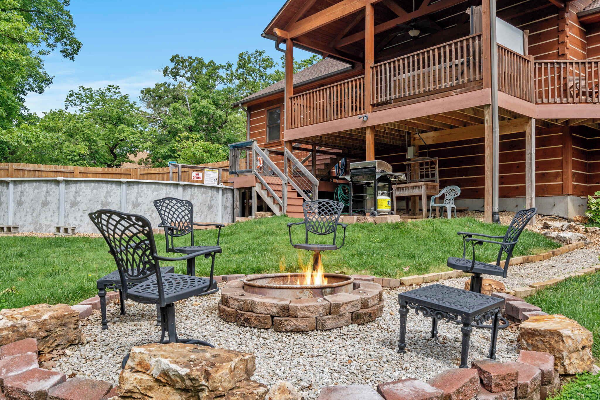 A wooden cabin with a deck, outdoor seating, and a fire pit.