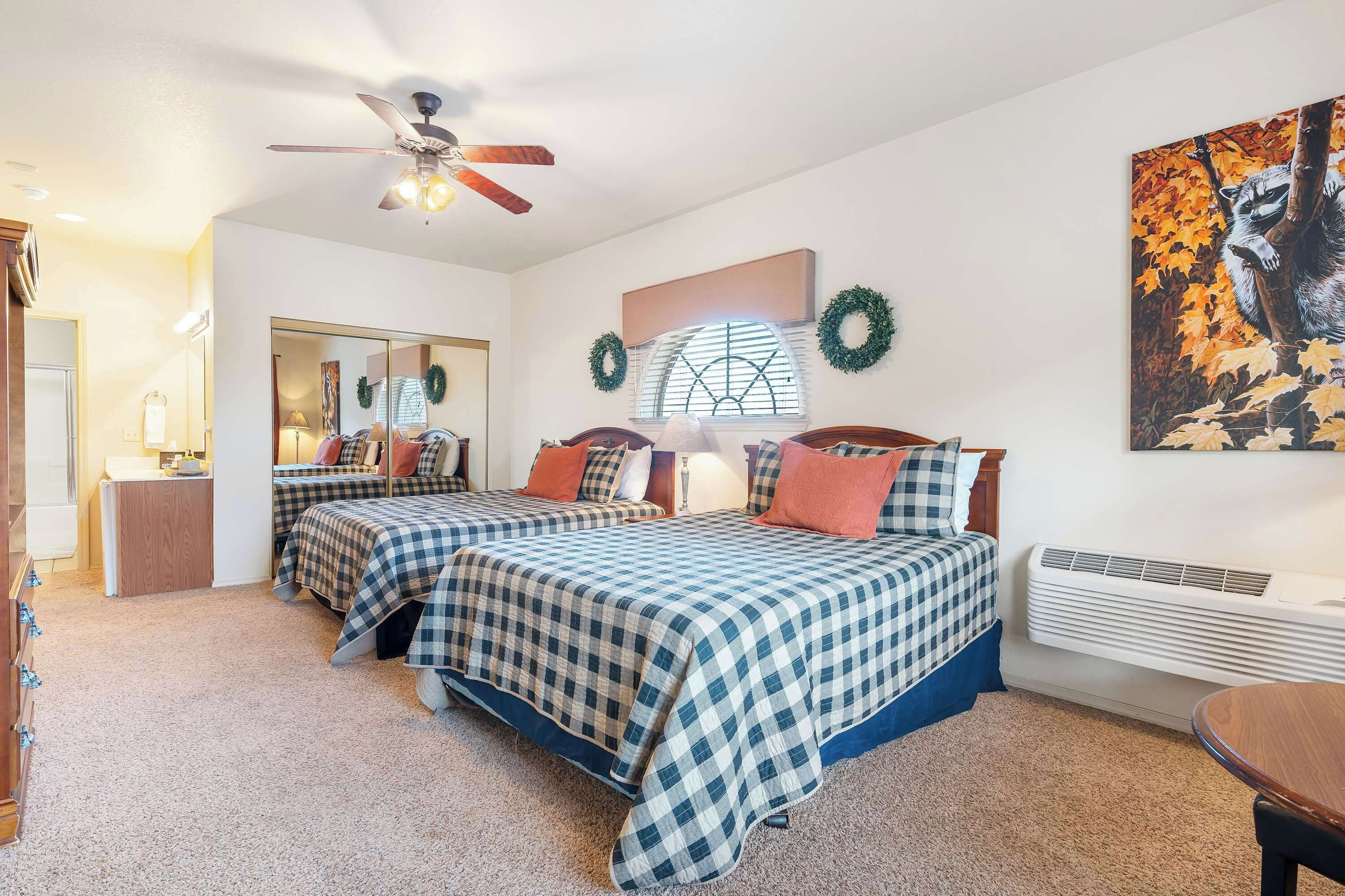 A bedroom with two beds, a ceiling fan, a heater, and a mirror.
