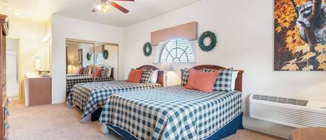 A bedroom with two beds, a ceiling fan, a heater, and a mirror.