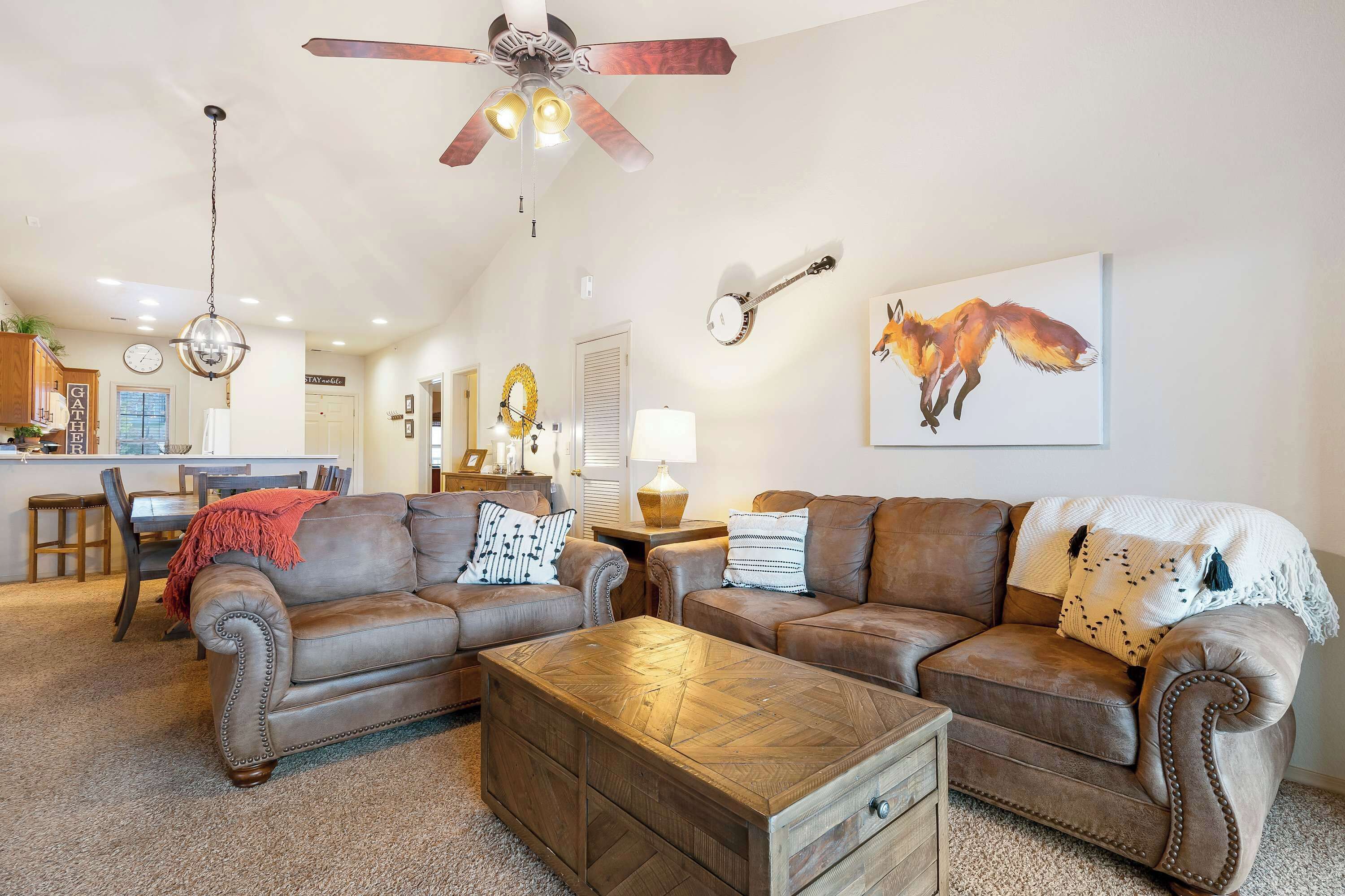 A living room with leather sofas, a wooden coffee table, and a ceiling fan.