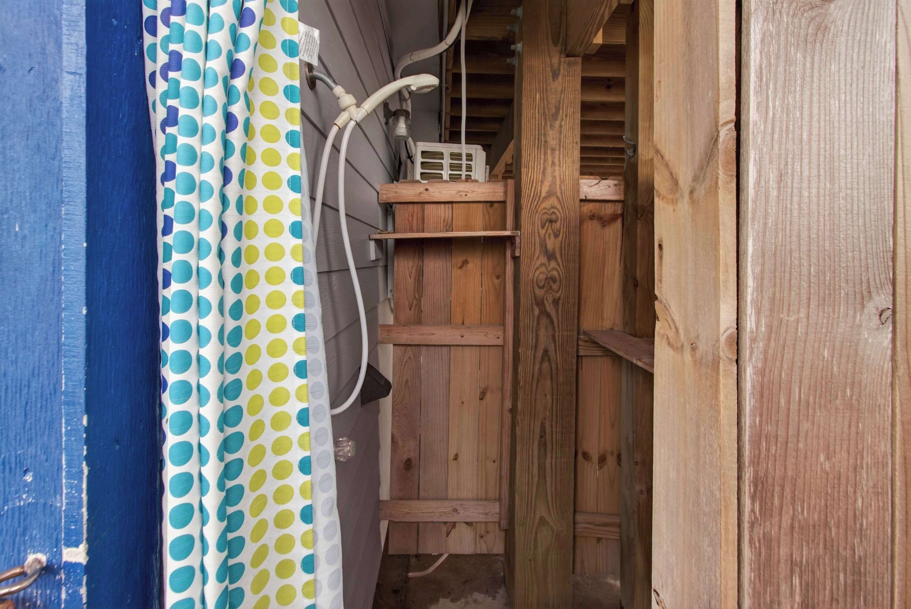 A wooden shed with a white plastic container on top, a blue wall with a white door, and a polka dot curtain.