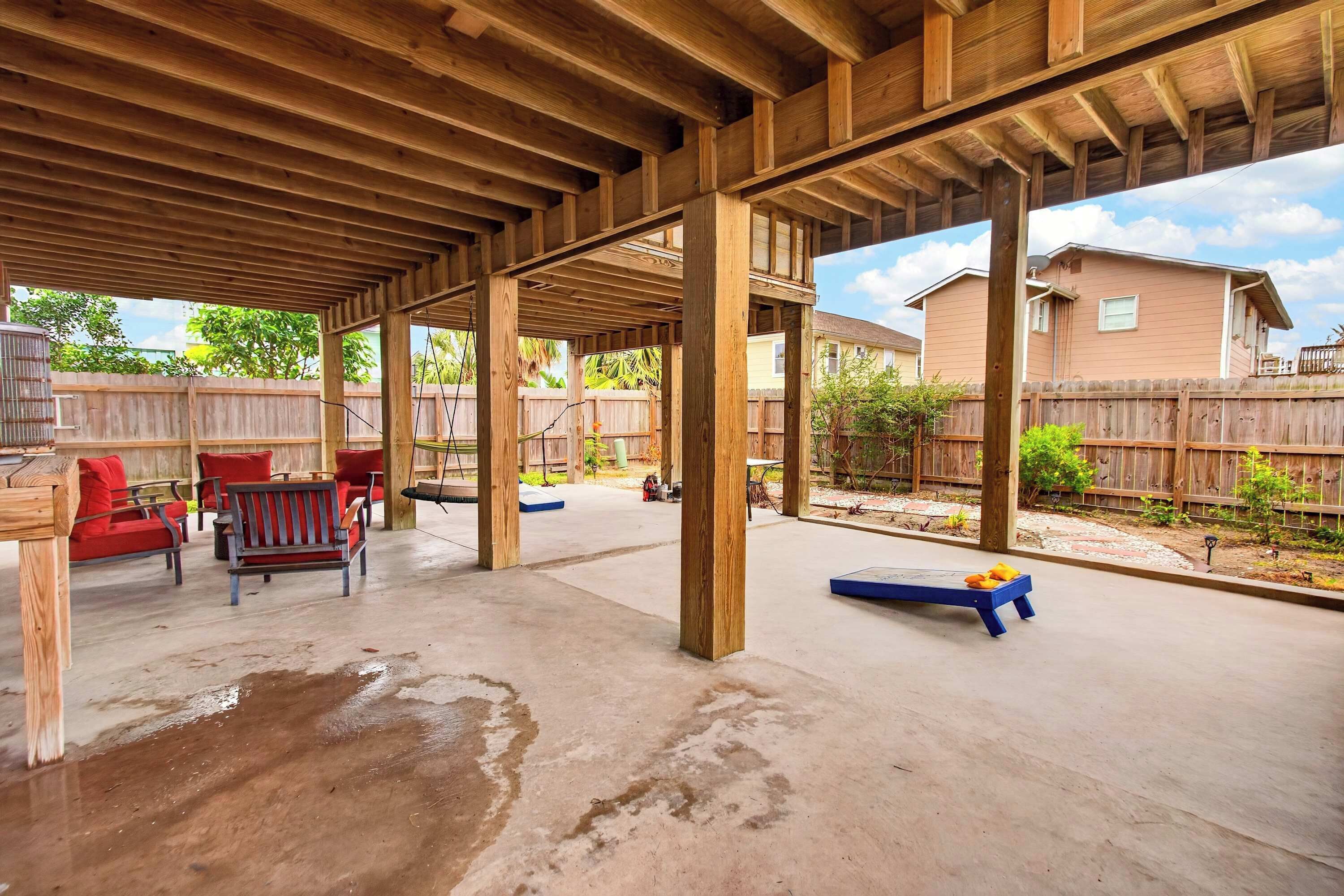 An open patio with a wooden ceiling, concrete floor, and outdoor furniture.