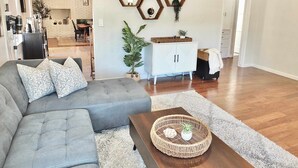A modern living room with a grey sofa, a wooden coffee table, and a white cabinet. - Bellflower Breeze Charming 3 BDR in Long Beach! (Long Beach)