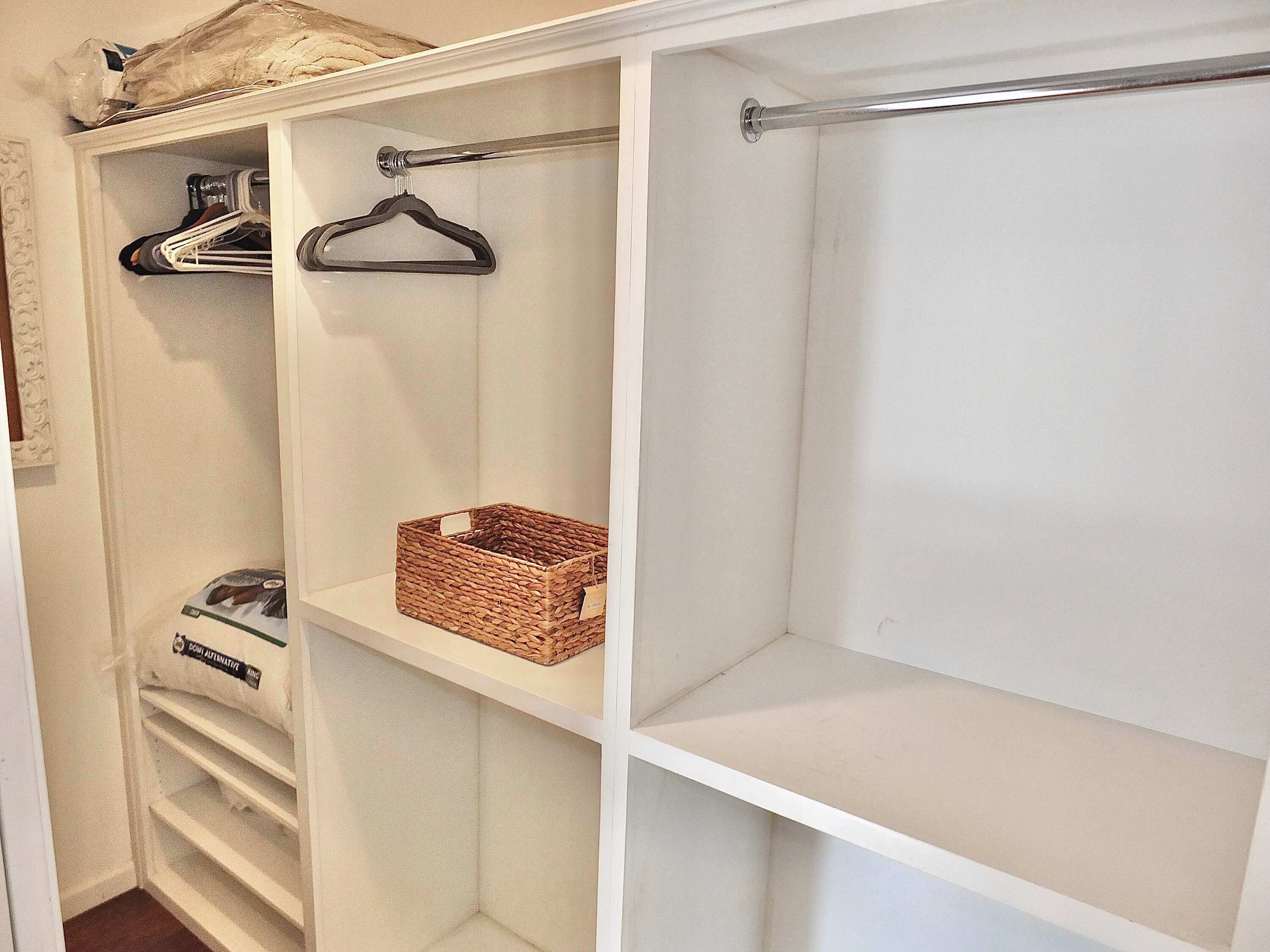 Un dressing accessible sans porte, avec des étagères ouvertes, une tringle et un panier posé sur une étagère.