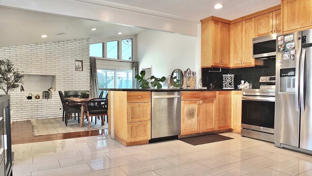 A modern kitchen with wooden cabinets, stainless steel appliances, and a tiled floor. - Bellflower Breeze Charming 3 BDR in Long Beach! (Long Beach)