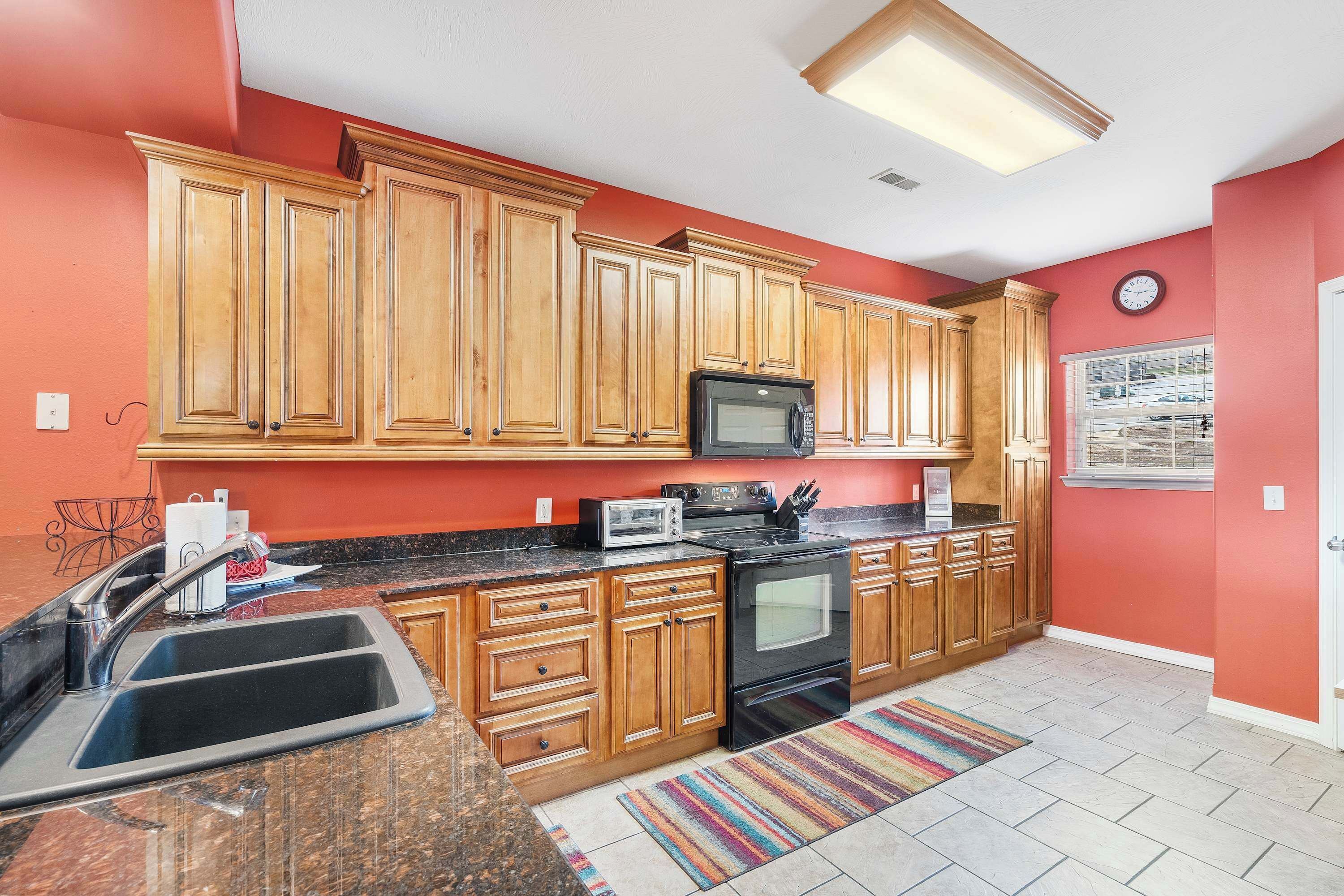 A kitchen with wooden cabinets, a black stove, a microwave, and a sink.