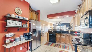 A modern kitchen with a refrigerator, coffee maker, and a coffee bar sign.