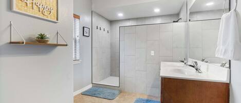 A modern bathroom with a shower, a sink, and a mirror.