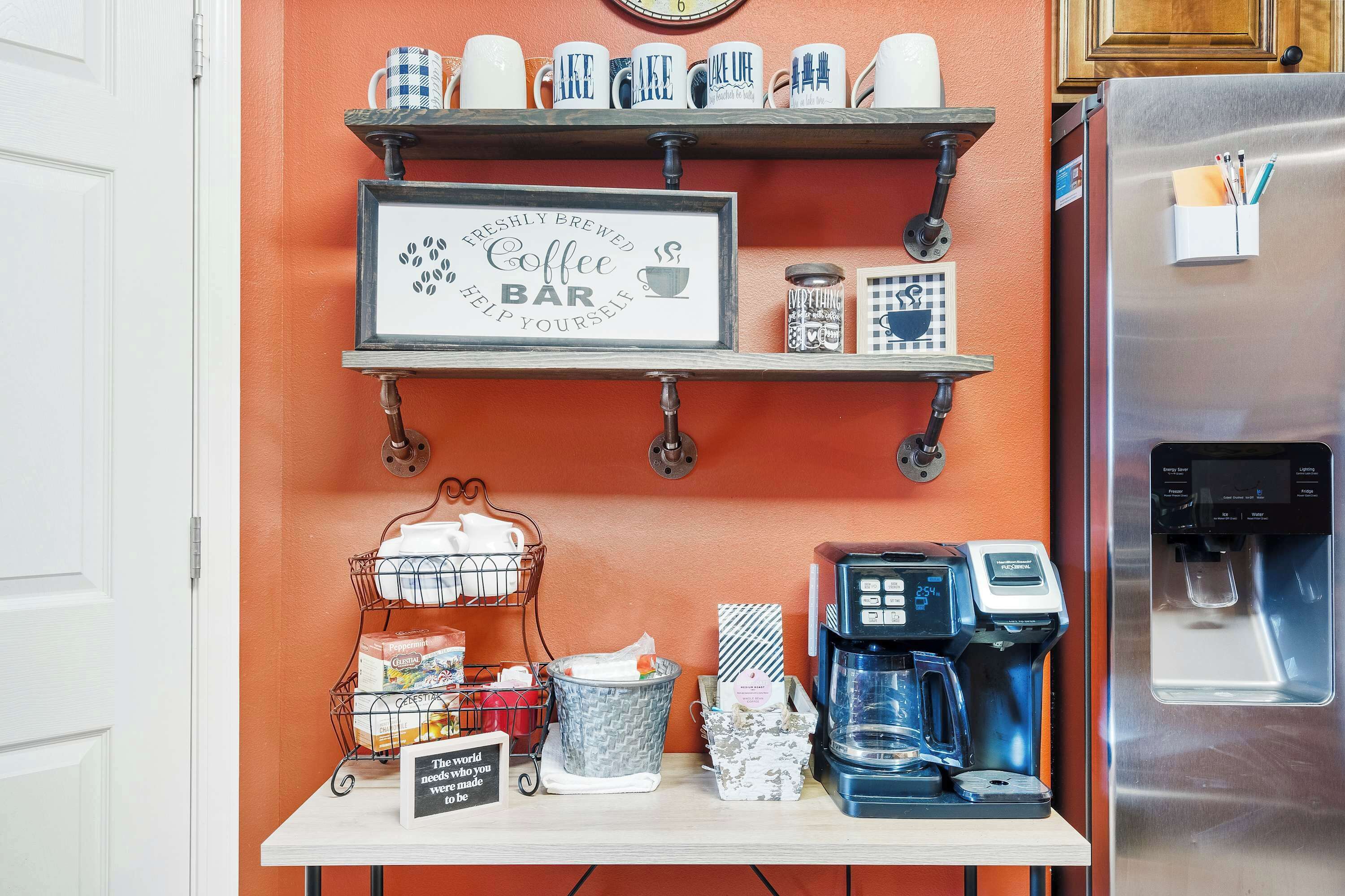 A kitchen area with a coffee bar, a coffee maker, a refrigerator, and various kitchen utensils.