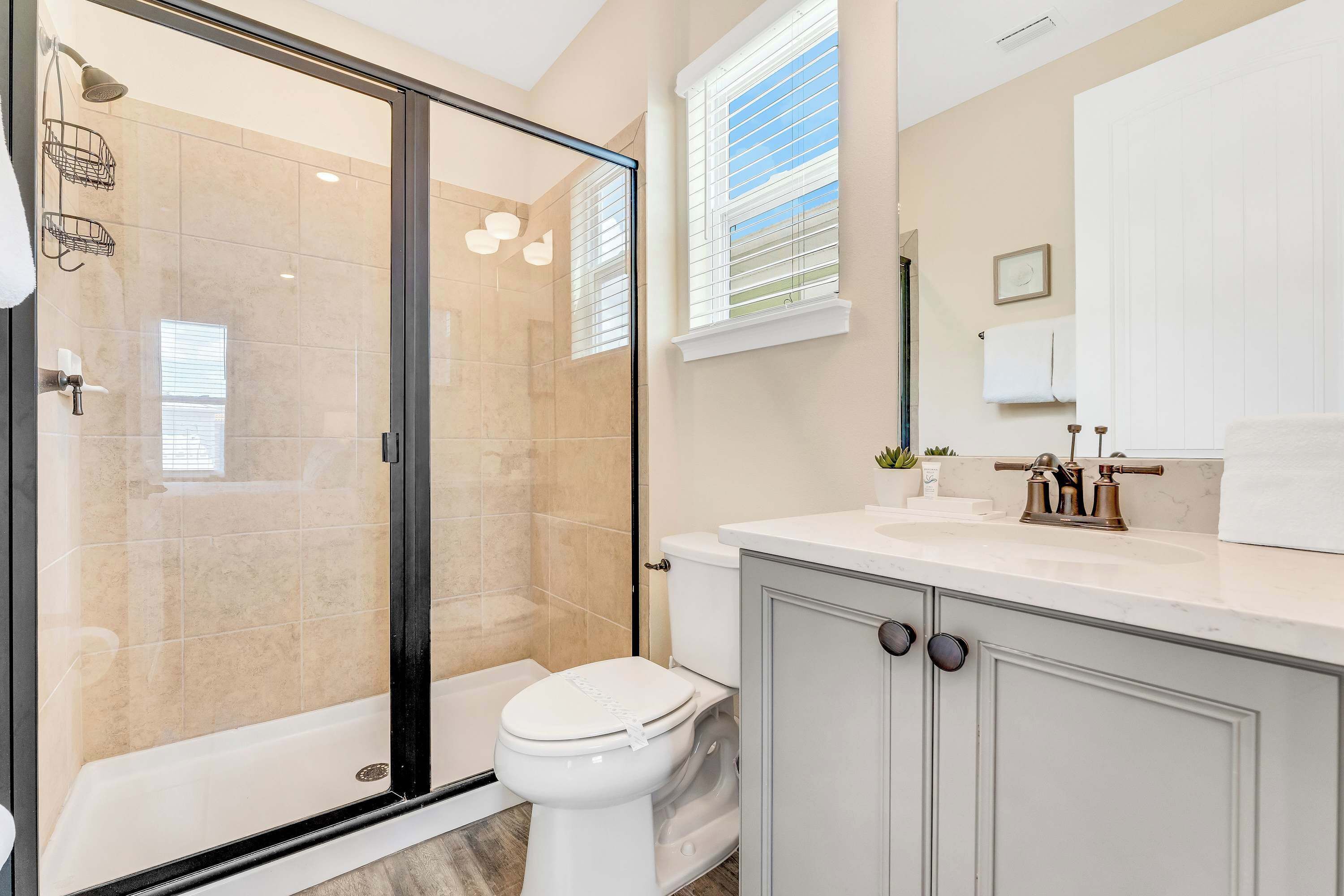 Une salle de bain moderne avec une douche à parois de verre, des toilettes et un meuble-lavabo avec un évier.