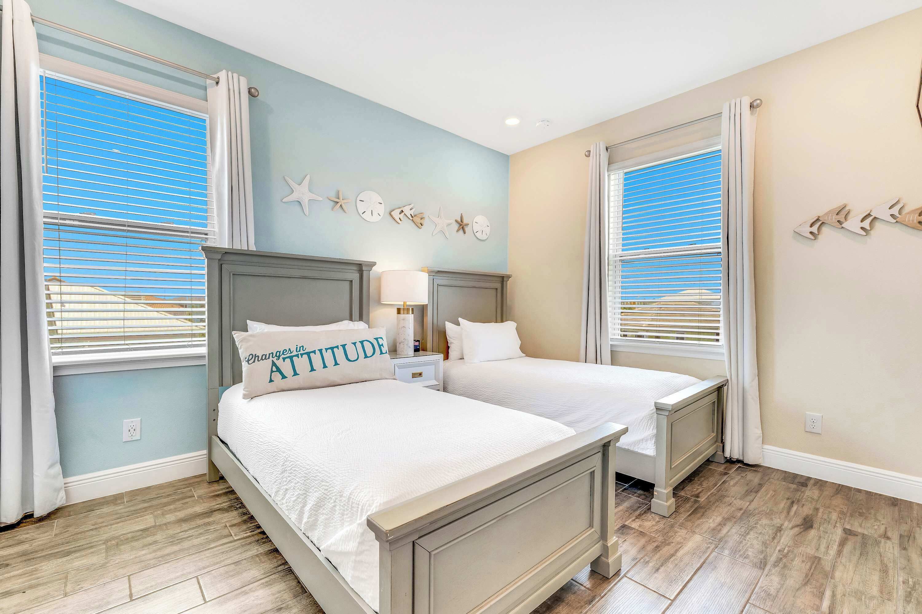 A bedroom with two beds, a nightstand, a lamp, and star-shaped wall decor.