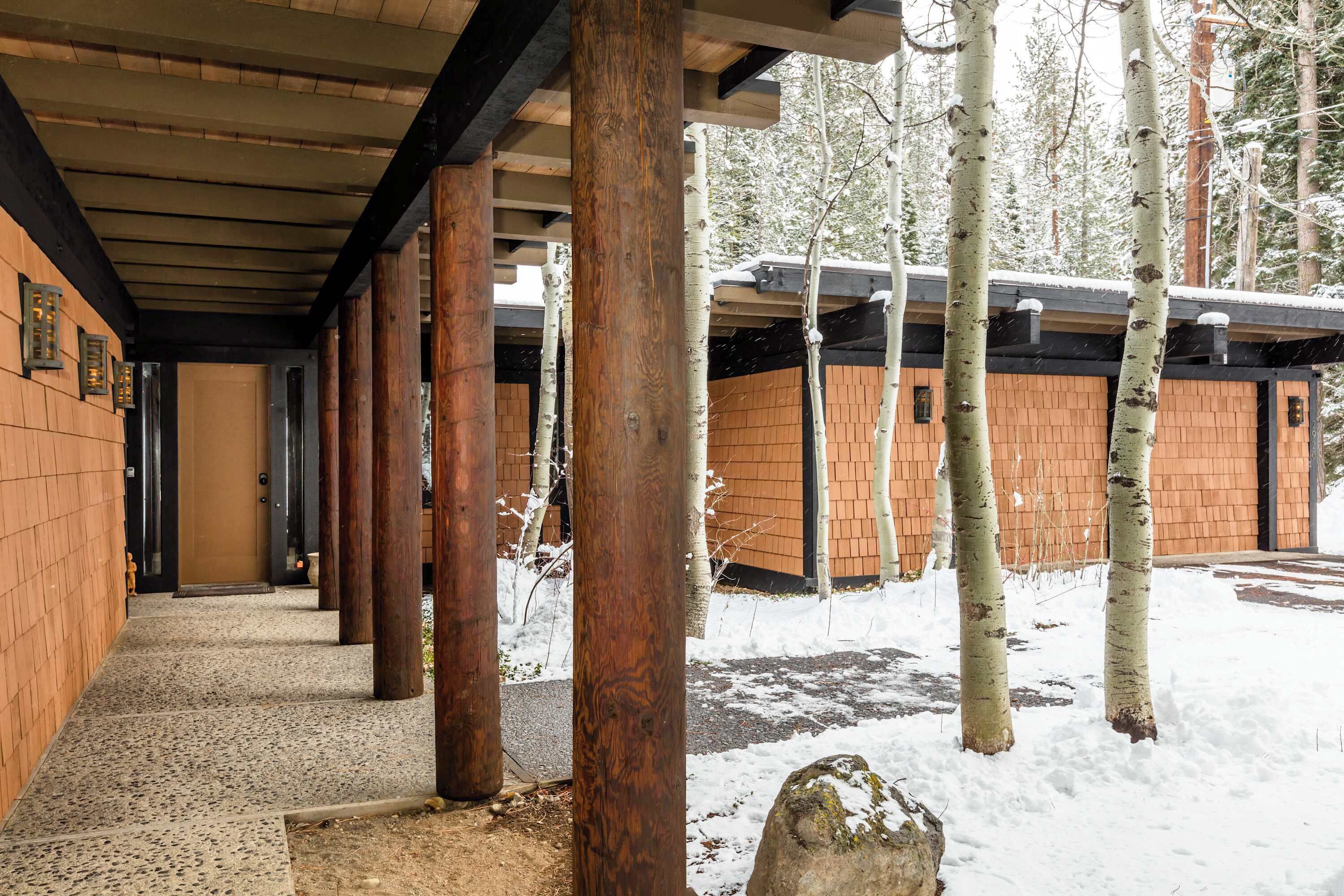 A covered walkway with wooden pillars, brick walls, and a snow-covered ground.
