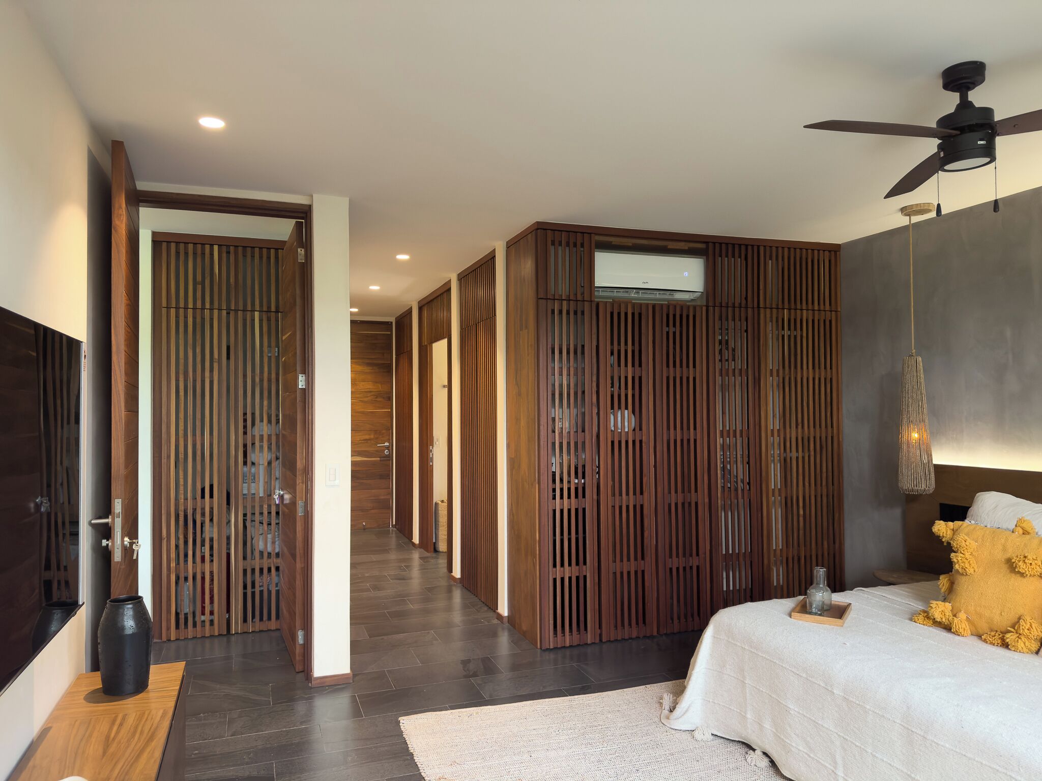 A modern bedroom with a bed, a ceiling fan, and a wooden wardrobe.