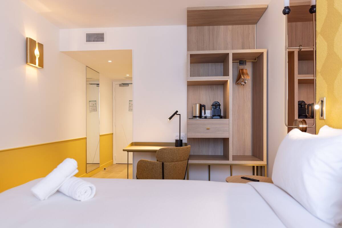 Une chambre d’hôtel avec un lit, un bureau, une chaise et une armoire.