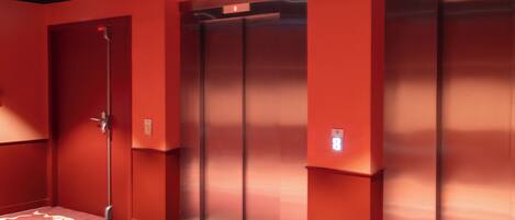 A hallway with red walls and a carpet with a white zigzag pattern.