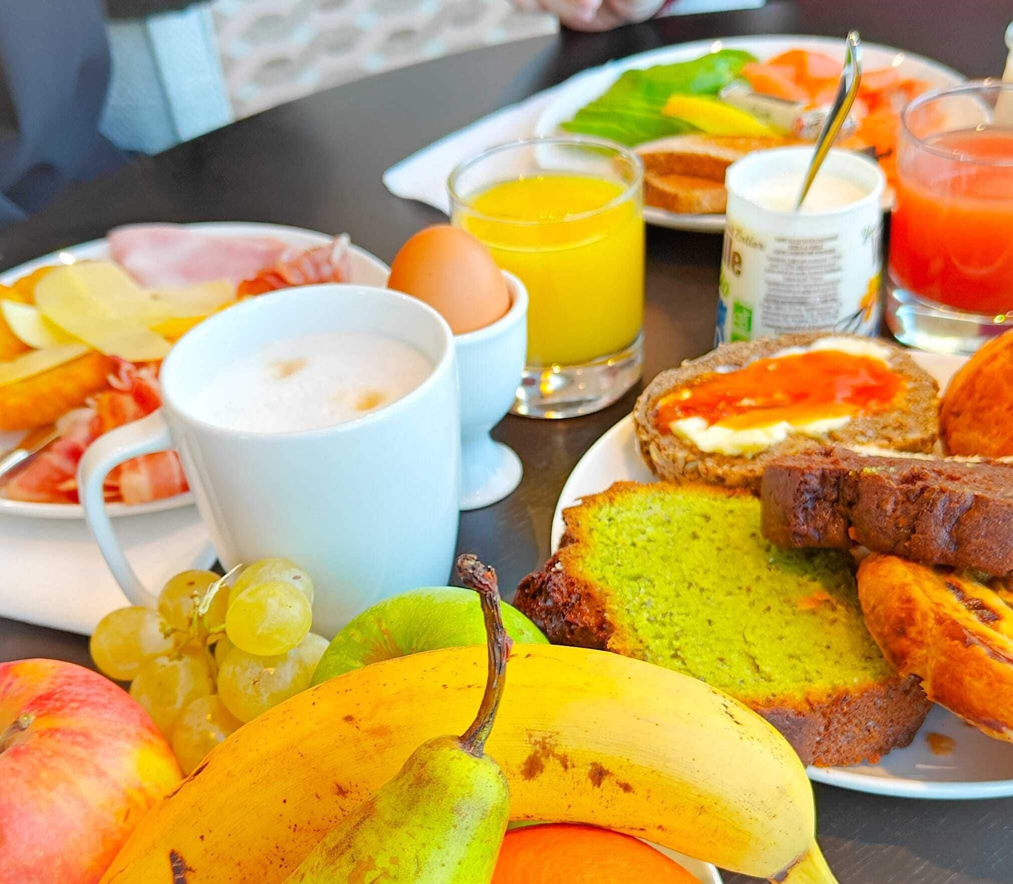 A breakfast table with various food items including fruits, bread, and beverages.