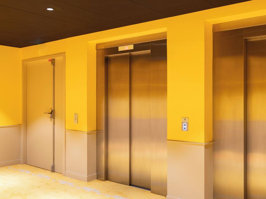 Un hall d’hôtel avec deux ascenseurs et une porte fermée.