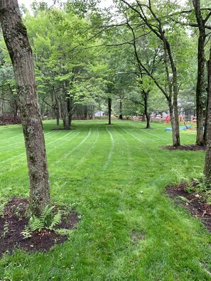 A well-maintained grassy area with trees and a wooden fence. - Mtn Modern Couples Retreat PetFriendly;FencedYard;Lake;Beach;Pool;JimThorpe;Ski (Albrightsville)