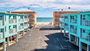 A beachfront hotel with two-story buildings, a parking area, and a view of the ocean. - The Hideaway A Gulf Shores Dream Vacation! (Gulf Shores)