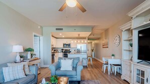 A spacious living room with a grey sofa, a coffee table with a basket, and a dining area with a white table and chairs. - Whitesands Retreat Incredible Resort Home! (Panama City Beach)