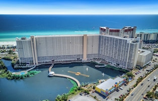 Um hotel grande com vários andares, um pátio central e vista para o oceano.